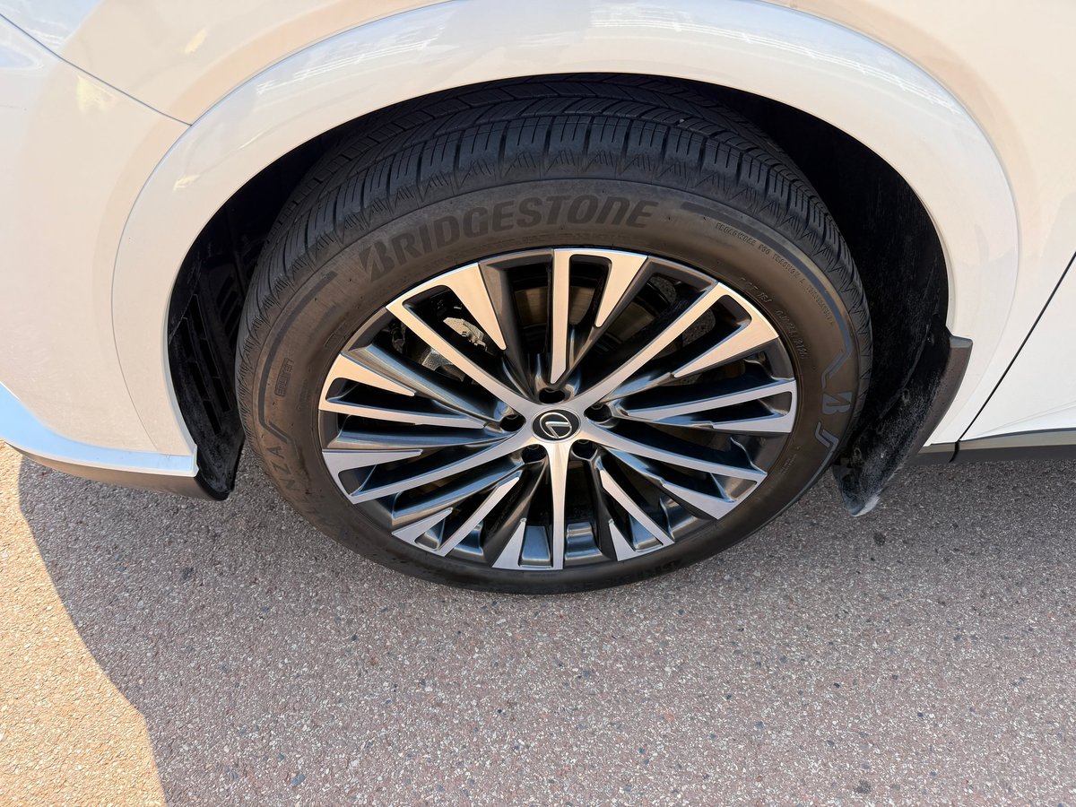 Close-up of a white Lexus's wheel with a black Bridgestone tire and multi-spoke alloy rim, freshly cleaned
